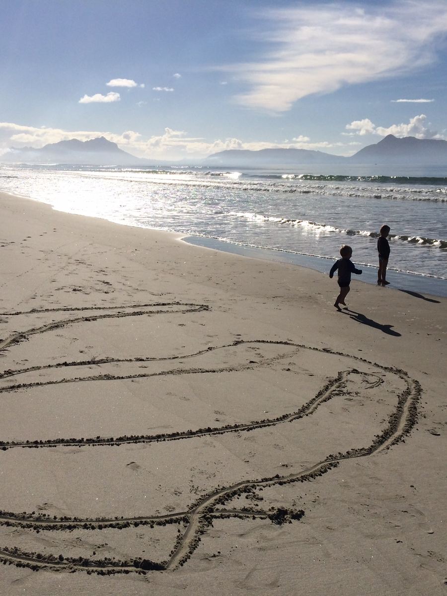 Bream Bay at low tide with a propeller drawn in the sand and the Whangarei Heads in the distance